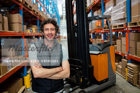 Warehouse worker with forklift in background