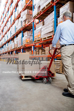 Warehouse manager in aisle with a pallet truck
