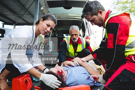 Injured man being healed by a team of ambulancemen