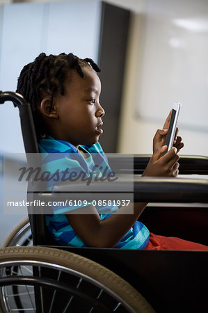 Disabled schoolboy on wheelchair using digital tablet