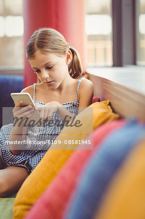 Girl sitting on sofa and using mobile phone