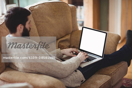 Close up view of hipster man using laptop in his sofa