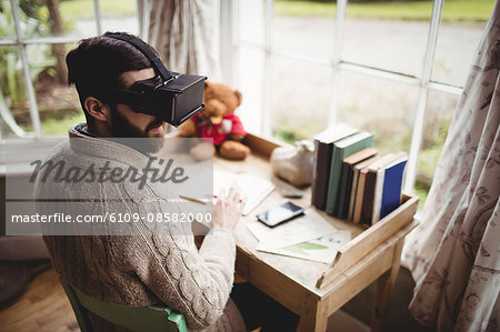 Hipster man using smart glasses while seating at desk