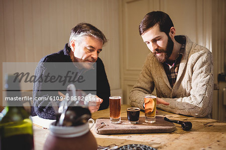 Mature and hipster man looking at shot on the table