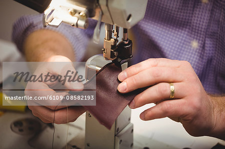 Close up of hands sewing a piece of leather