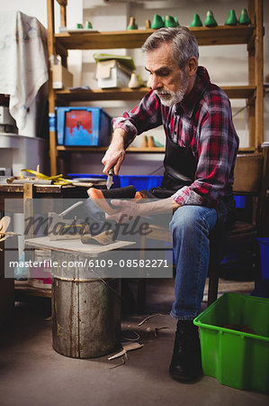 Portrait of cobbler using a knife on a shoe