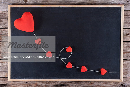 Red hearts kite on blackboard with wooden background