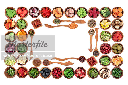 Paleo diet health and super food of fruit, herbs, vegetables, nuts and seeds in wooden bowls forming an abstract border over white background. High in vitamins, antioxidants, minerals and anthocyanins.