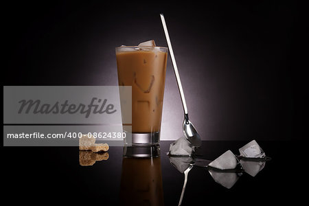 Delicious ice coffee with melting ice cubes and brown sugar on dark background. Culinary gourmet luxurious coffee drinking.