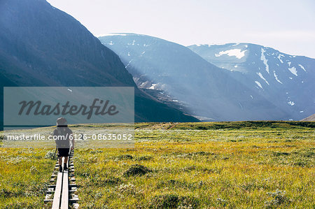 Sweden, Lapland, Ladtjovagge, Kungsleden, Rear view of male hiker walking along boardwalk