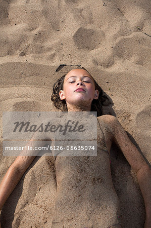 Sweden, Dalarna, Girl (10-11) lying in sand on beach