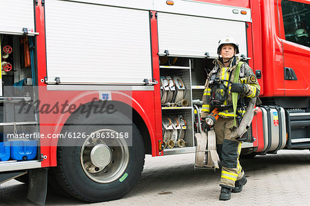 Sweden, Female firefighter with equipment standing next to fire truck looking up