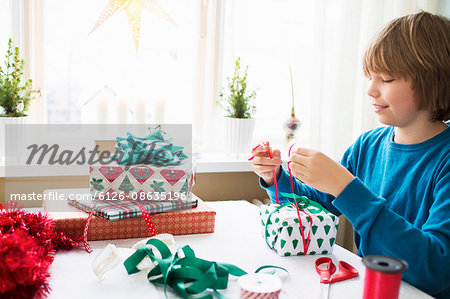 Boy (10-11) wrapping Christmas presents