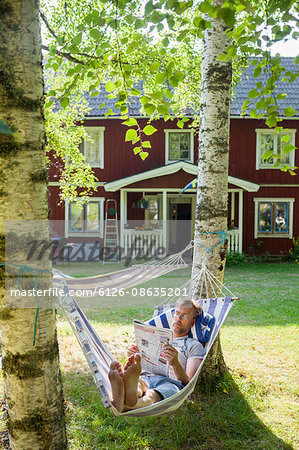 Sweden, Narke, Finnerodja, View man reading in hammock