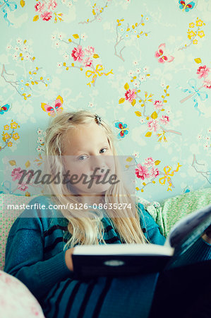 Sweden, Girl (6-7) reading book in bedroom