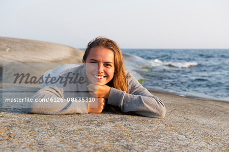 Sweden, Stockholms Archipelago, Sodermanland, Haninge, Norsten, Girl (12-13) resting on rock at seaside