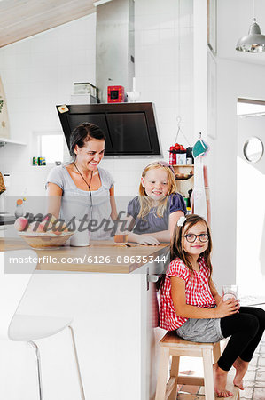 Sweden, Mother and daughters (6-7, 8-9) smiling in kitchen