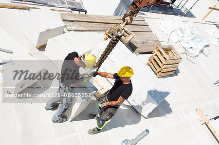 Sweden, Ostergotland, Linkoping, Construction workers adjusting blocks on construction site
