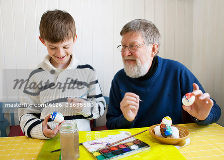 Grandfather with grandson (8-9) decorating Easter eggs