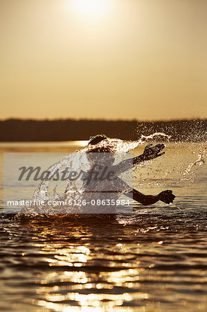 Sweden, Vastra Gotaland, Skagern, Boy (10-11) splashing in lake at sunset