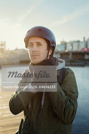 Sweden, Sodermanland, Stockholm, Sodermalm, Slussen, Outdoor portrait of mid adult man tying helmet strap