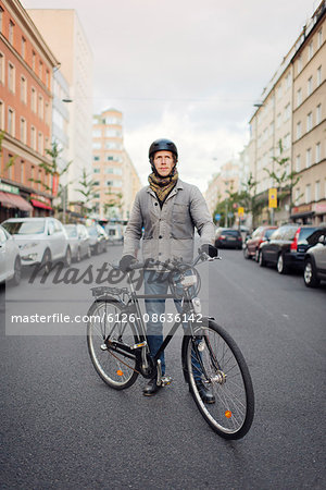 Sweden, Sodermanland, Stockholm, Sodermalm, Hornstull, Mid adult man standing by his bicycle on street