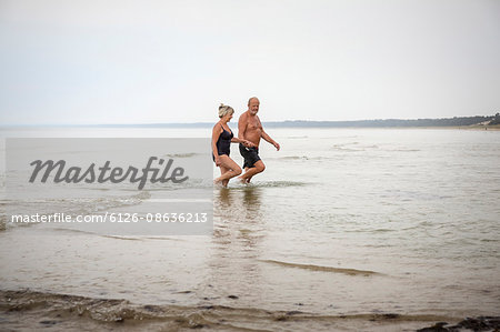 Sweden, Skane, Ahus, Senior couple wading in water
