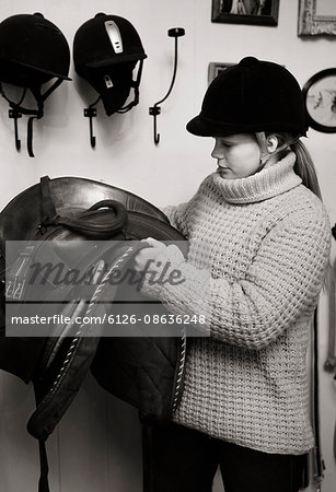 Sweden, Young woman preparing saddle