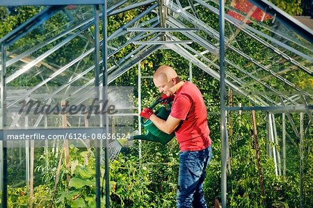 Finland, Paijat-Hame, Heinola, Man watering plants in greenhouse