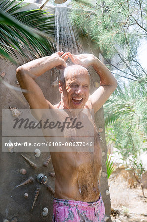 Greece, Cyclades, smiling man taking a shower at the beach