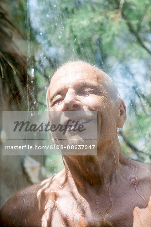 Close-up of smiling man taking a shower inside