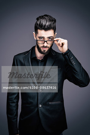 Portrait of a young businessman holding a pair of glasses, look toward the lens