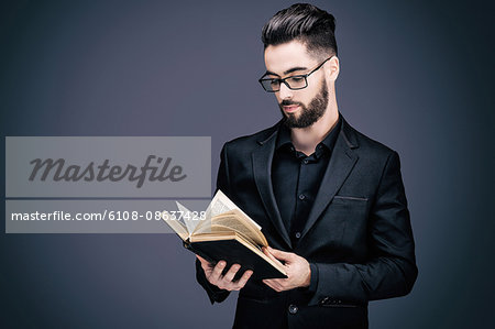 Portrait of a young man in a suit reading a book