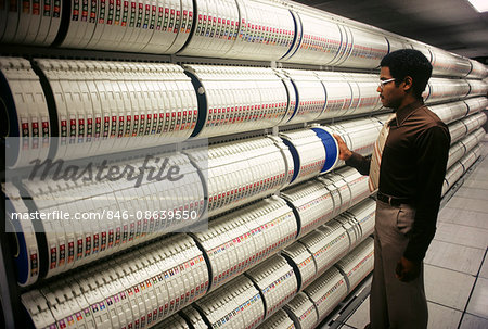 1980s AFRICAN AMERICAN MAN FILING COMPUTER TAPE REELS