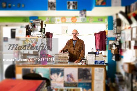 Portrait of mature man in record shop, leaning on stack of records