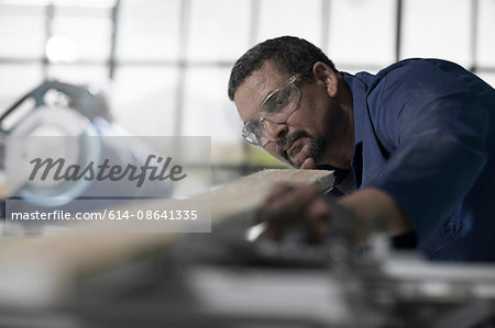 Carpenter checking straightness of plank in workshop