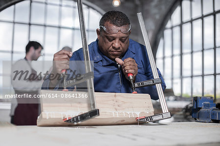 Carpenter gluing and clamping wood in workshop