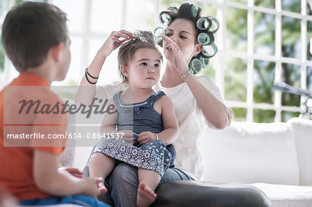 Mother in hair rollers, rolling daughter's hair