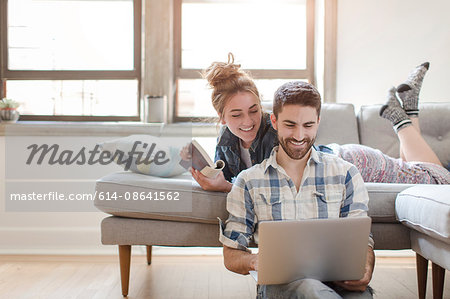 Young couple relaxing at home, looking at laptop