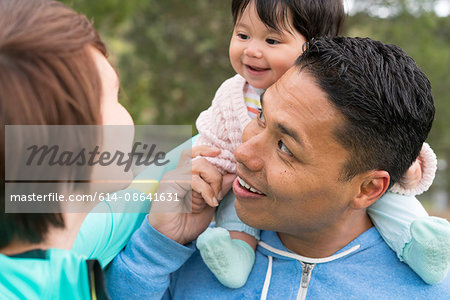 Couple playing piggyback ride with baby in park