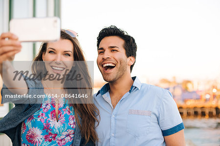 Young couple taking smartphone selfie on pier, Santa Monica, California, USA