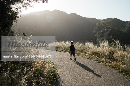 Boy walking along rural road, Santa Barbara, California, USA
