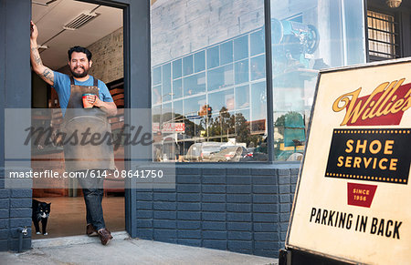 Portrait of male cobbler leaning against shoe shop doorway