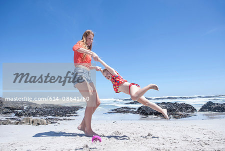 Young woman holding and spinning girl on beach, Cape Town, South Africa