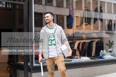 Sweden, Uppland, Stockholm, Sales clerk standing in front of clothing store