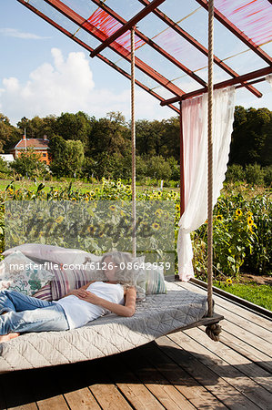 Sweden, Uppland, Solna, Ulriksdal, Woman sleeping on swing in Ulriksdals Handelstradgard