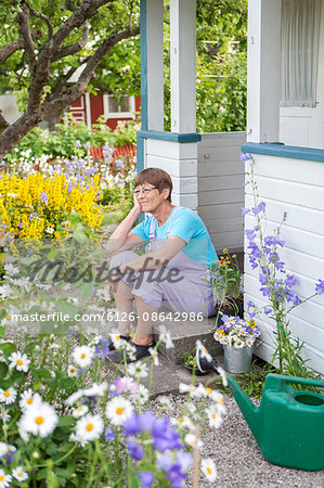 Sweden, Skane, Woman sitting at front stoop of garden house