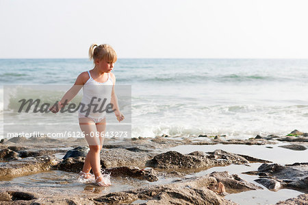 Turkey, Alanya, Blonde girl (4-5) walking on rock beach