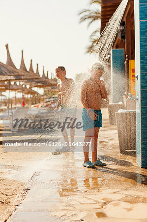 Turkey, Alanya, Boy (10-11) and girl (8-9) standing under shower on beach