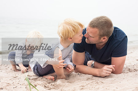 Sweden, Gotland, Ljugarn, Two boys (2-3, 4-5) spending time with man on beach